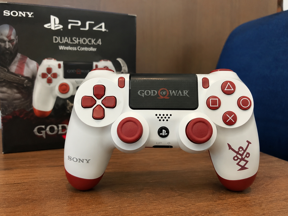 دسته بازی PS4 طرح God of War سفید قرمز روی میز گیمینگ با طراحی خاص و جذاب برای گیمرها.
